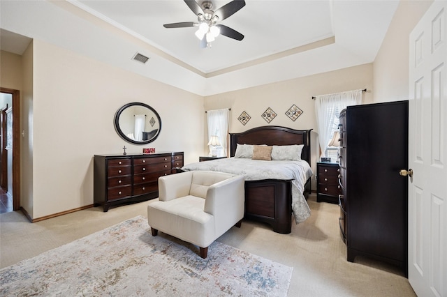 bedroom featuring a raised ceiling, visible vents, a ceiling fan, light carpet, and baseboards