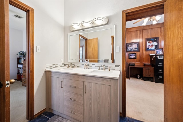 full bath featuring double vanity, tasteful backsplash, visible vents, ceiling fan, and a sink