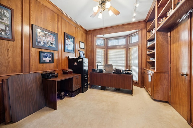 home office with rail lighting, light carpet, ceiling fan, and wood walls