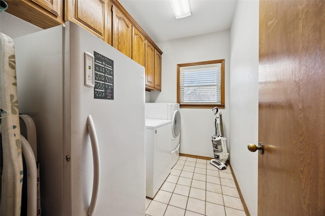 laundry room with light tile patterned floors, washing machine and clothes dryer, cabinet space, and baseboards