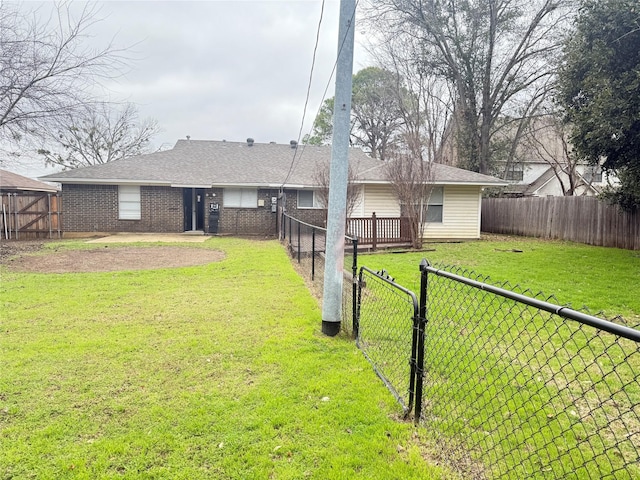 back of property featuring a fenced backyard, brick siding, a yard, roof with shingles, and a gate