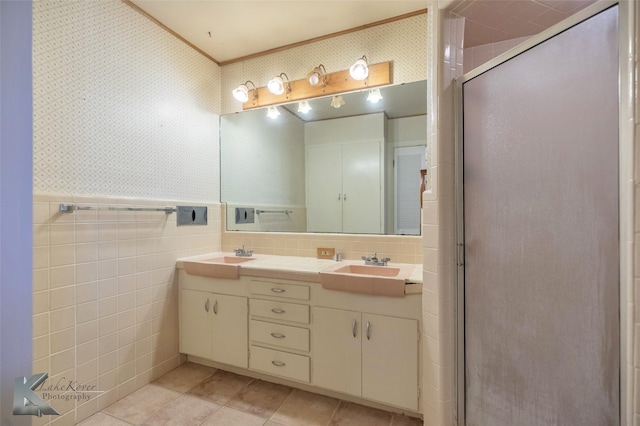 bathroom featuring wallpapered walls, tile patterned floors, a sink, and a stall shower