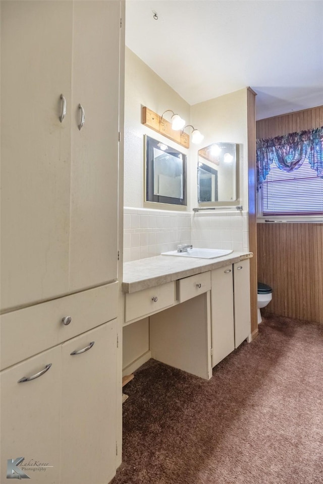 bathroom with a wainscoted wall, toilet, vanity, and tile walls