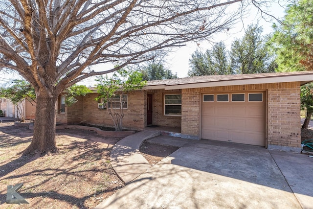 single story home featuring a garage, concrete driveway, and brick siding