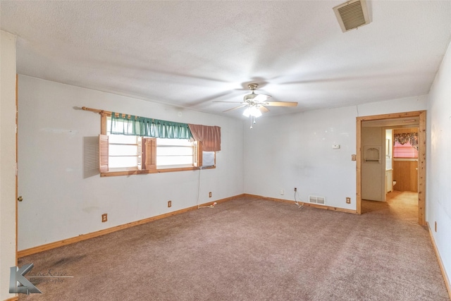 carpeted spare room with visible vents, a textured ceiling, and baseboards