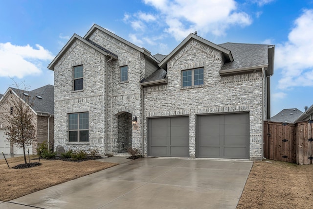 french provincial home with a garage, a shingled roof, brick siding, fence, and concrete driveway