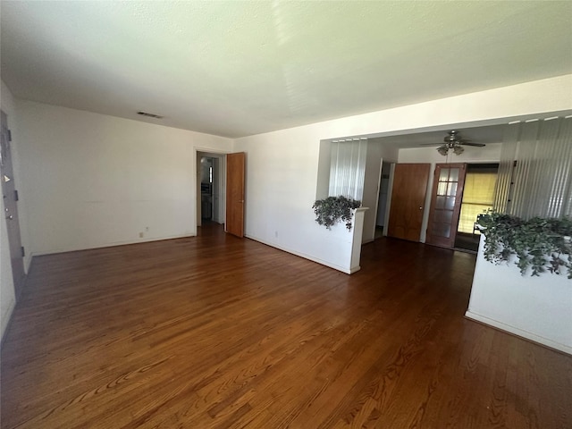 empty room featuring ceiling fan, visible vents, and dark wood finished floors