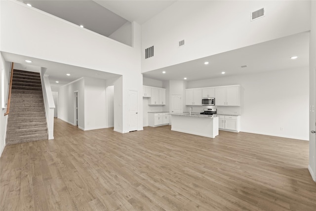 2720 Green River Rd, Royse City, TX 75189 - unfurnished living room with a high ceiling, light wood finished floors, baseboards, stairs, and recessed lighting