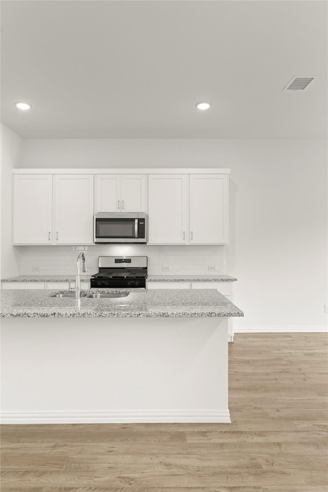 2720 Green River Rd, Royse City, TX 75189 - kitchen with appliances with stainless steel finishes, white cabinetry, backsplash, light stone countertops, and recessed lighting