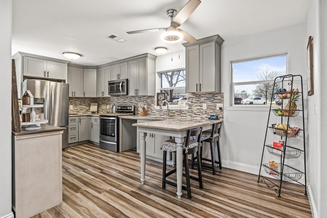 kitchen featuring stainless steel appliances, tasteful backsplash, gray cabinets, and visible vents