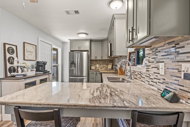 kitchen featuring appliances with stainless steel finishes, gray cabinets, visible vents, and a kitchen breakfast bar