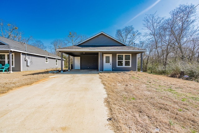 view of front of house featuring driveway, an attached carport, and roof with shingles