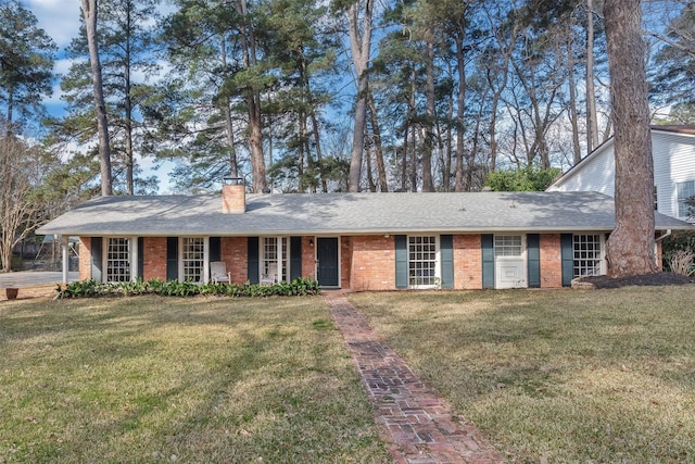 ranch-style house with roof with shingles, a chimney, a front lawn, and brick siding