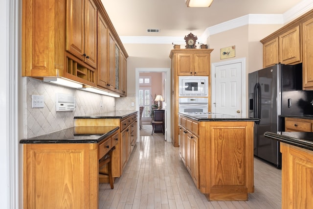 kitchen featuring brown cabinetry, white appliances, visible vents, and a kitchen island