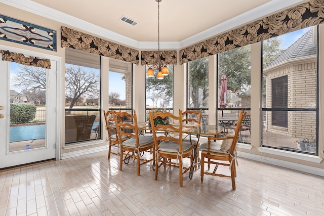 dining space with crown molding, wood finished floors, visible vents, and a healthy amount of sunlight