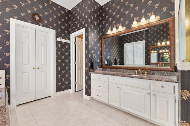 full bath with wallpapered walls, tile patterned flooring, baseboards, and vanity