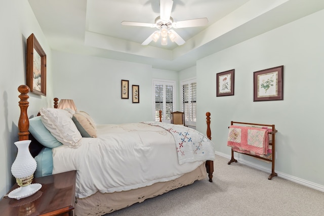 bedroom with baseboards, a raised ceiling, a ceiling fan, and light colored carpet