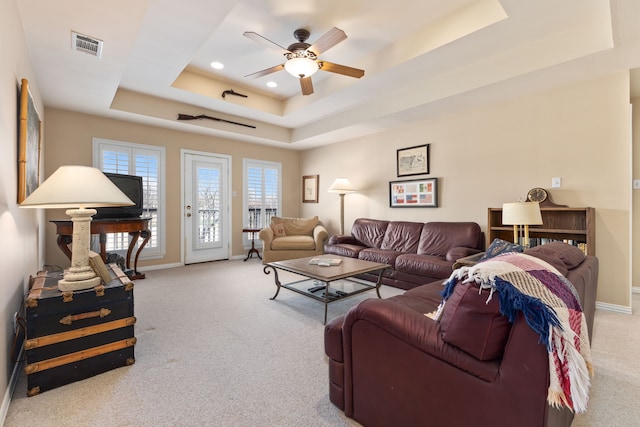 living room featuring light carpet, baseboards, visible vents, and a raised ceiling