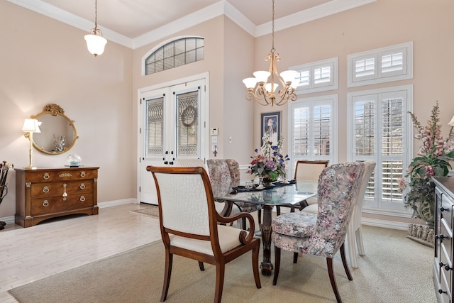 dining space with baseboards, light wood finished floors, a towering ceiling, and crown molding