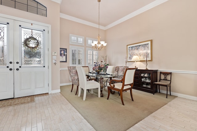 dining area with light wood-style flooring, a chandelier, baseboards, and ornamental molding