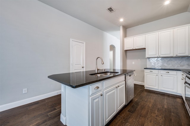 kitchen featuring a kitchen island with sink, white cabinetry, a sink, and arched walkways