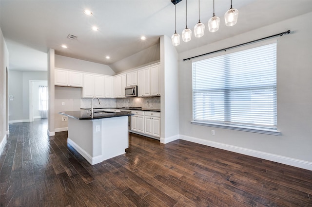 kitchen featuring dark countertops, a sink, white cabinetry, and stainless steel microwave