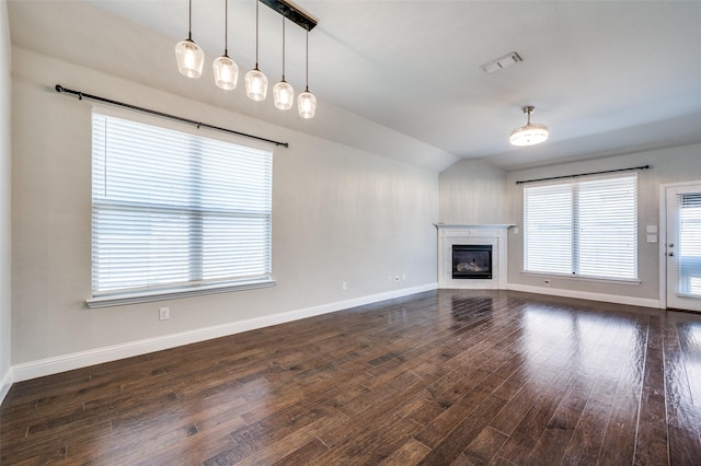 unfurnished living room featuring dark wood-style floors, a glass covered fireplace, visible vents, and baseboards