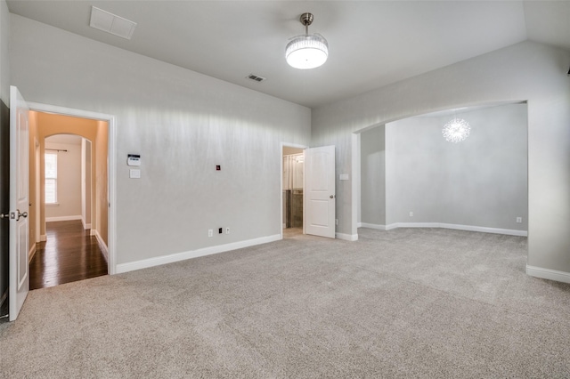 interior space featuring baseboards, visible vents, arched walkways, vaulted ceiling, and carpet floors