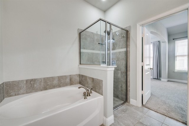 bathroom featuring a stall shower, baseboards, a bath, and tile patterned floors