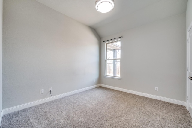 empty room with lofted ceiling, carpet floors, and baseboards