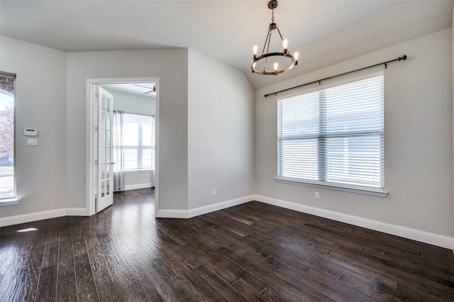 spare room with dark wood-type flooring, a chandelier, vaulted ceiling, and baseboards