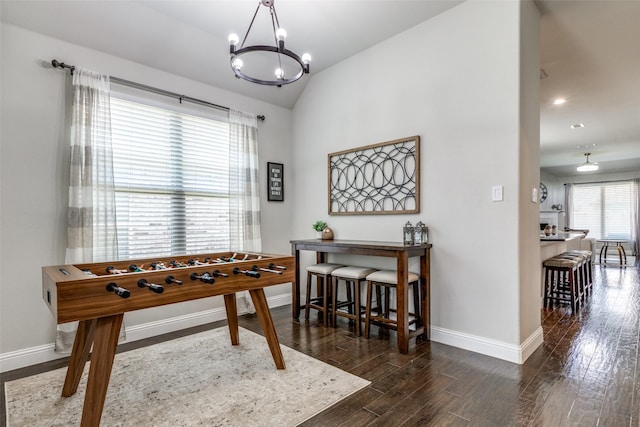 game room featuring an inviting chandelier, baseboards, vaulted ceiling, and dark wood-type flooring