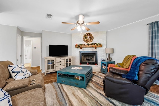 living area featuring ornamental molding, wood finished floors, visible vents, and a ceiling fan