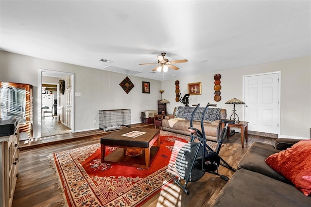 living area with visible vents, dark wood-type flooring, a ceiling fan, and baseboards