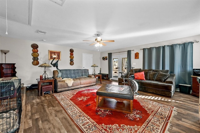 living area featuring attic access, visible vents, ceiling fan, and dark wood-style flooring