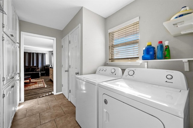 laundry area featuring cabinet space, light tile patterned floors, and washer and clothes dryer