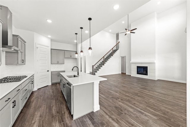 551 Baker Ct, Fate, TX 75189 - kitchen with stainless steel appliances, wall chimney exhaust hood, a sink, gray cabinetry, and a ceiling fan