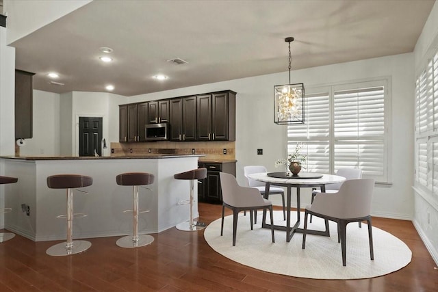 kitchen with dark wood finished floors, decorative backsplash, stainless steel microwave, dark brown cabinets, and recessed lighting