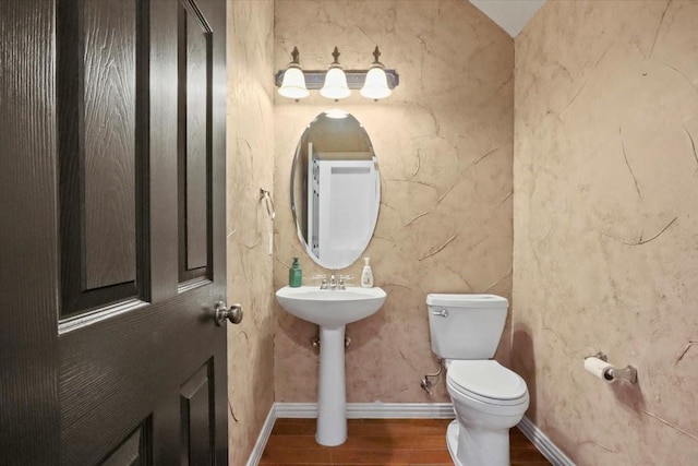 half bath featuring toilet, baseboards, and wood finished floors