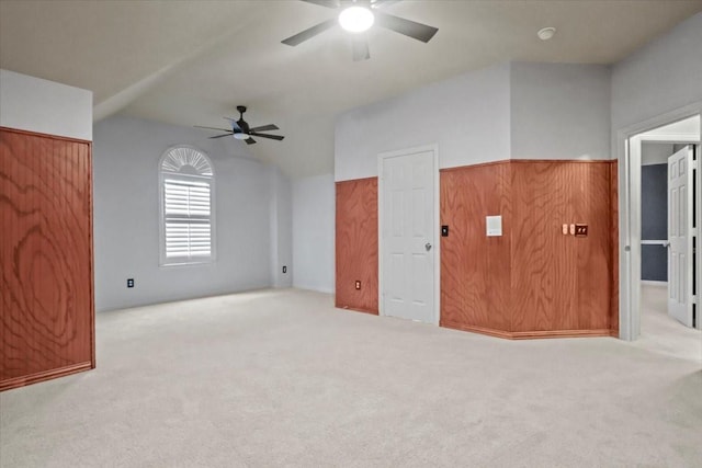 additional living space with vaulted ceiling, carpet floors, wood walls, and ceiling fan