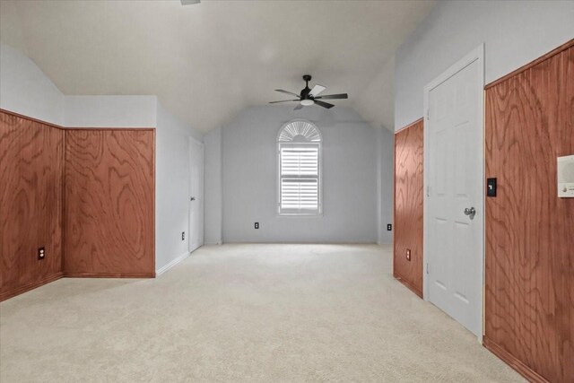 bonus room featuring vaulted ceiling, wood walls, carpet, and a ceiling fan