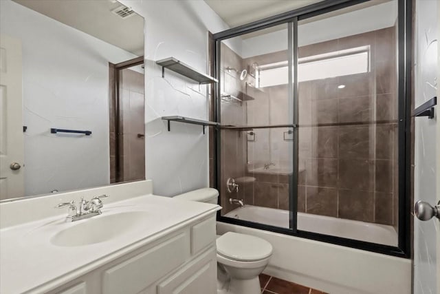 bathroom featuring visible vents, toilet, combined bath / shower with glass door, vanity, and tile patterned flooring