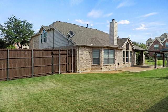 back of property featuring brick siding, a patio, a chimney, a lawn, and fence