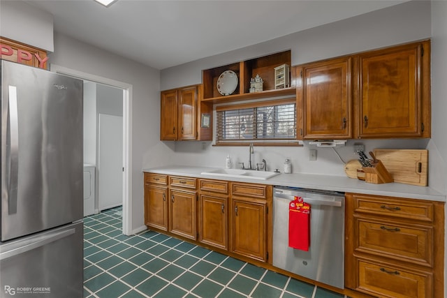 kitchen with stainless steel appliances, a sink, light countertops, and brown cabinets