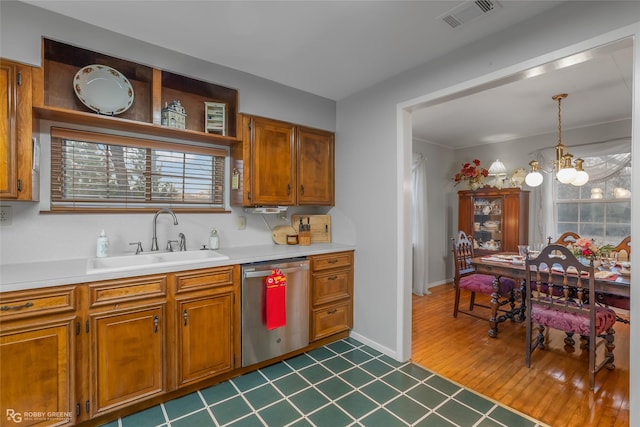 kitchen with light countertops, hanging light fixtures, visible vents, stainless steel dishwasher, and a sink