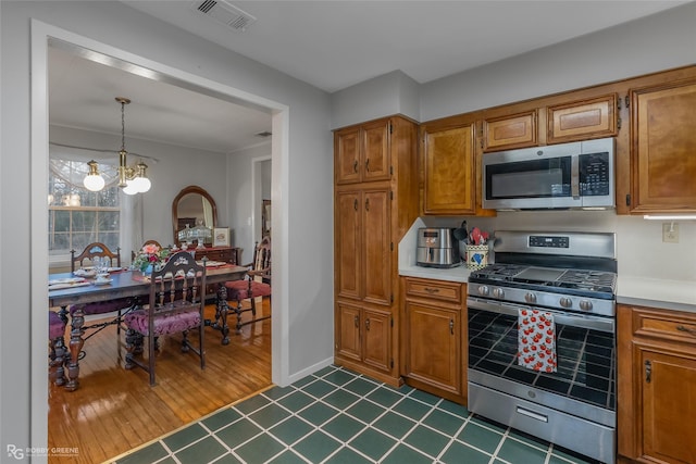 kitchen featuring appliances with stainless steel finishes, light countertops, visible vents, and hanging light fixtures