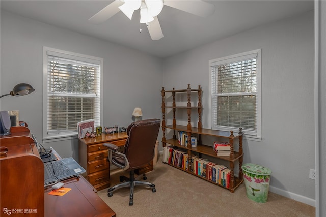 carpeted office space featuring a ceiling fan and baseboards