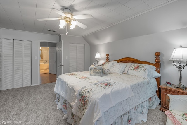 bedroom with ceiling fan, light colored carpet, visible vents, vaulted ceiling, and two closets