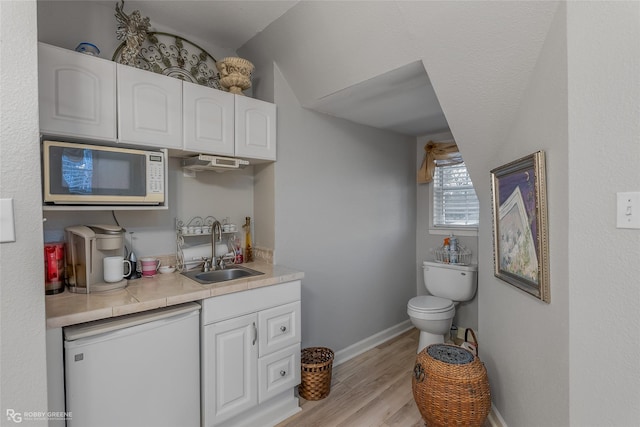 bathroom featuring toilet, wood finished floors, vanity, and baseboards