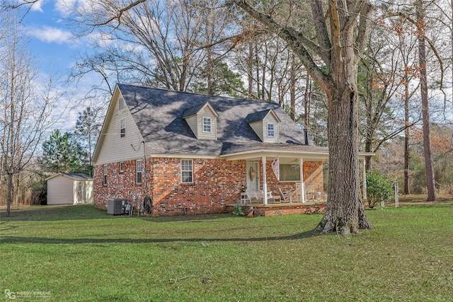 cape cod-style house with central AC unit, an outdoor structure, a shed, a front lawn, and brick siding